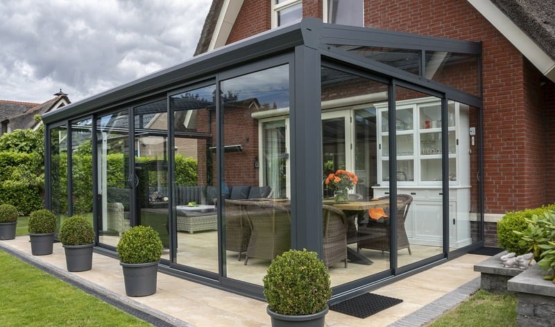 Véranda moderne avec grandes baies vitrées et mobilier contemporain